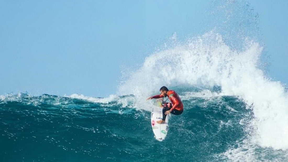A man surfing in a red rash vest