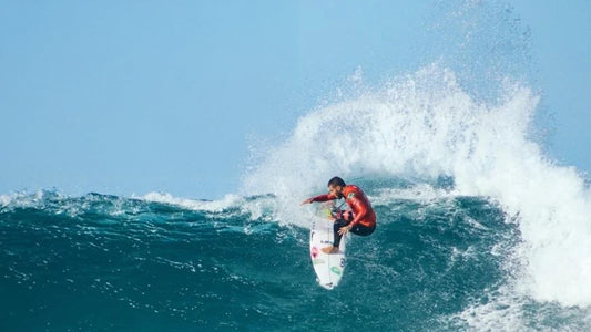A man surfing in a red rash vest