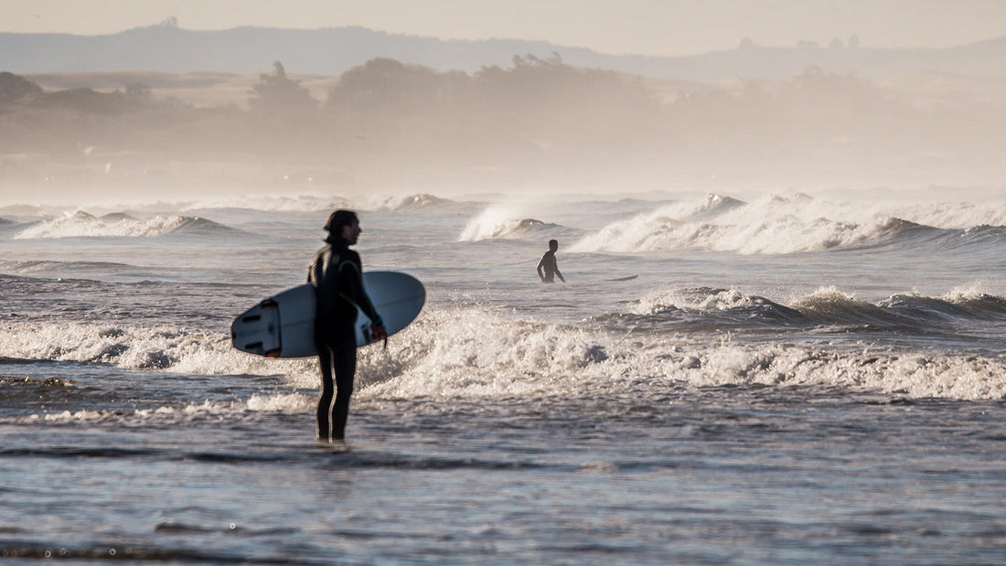 Surfer standing on beach looking at the wave breaks