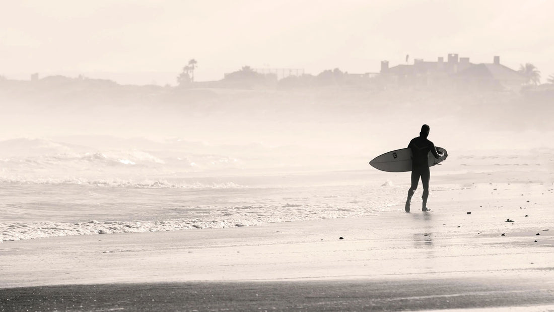surfer walking on a beach - Choosing Surfboards For Beginners