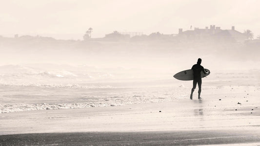 surfer walking on a beach - Choosing Surfboards For Beginners