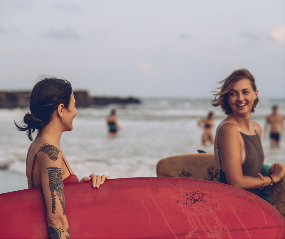 Two girls holding surfboards