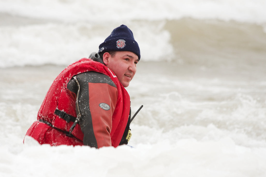 A man in the sea wearing a drysuit and hat
