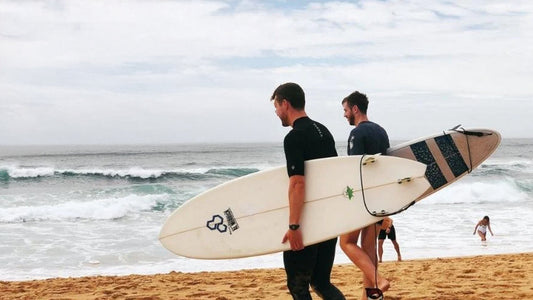 Two men carrying their surfboards to the sea