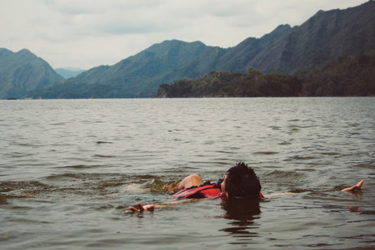 A man wearing a flotation device lying on his back in a lake