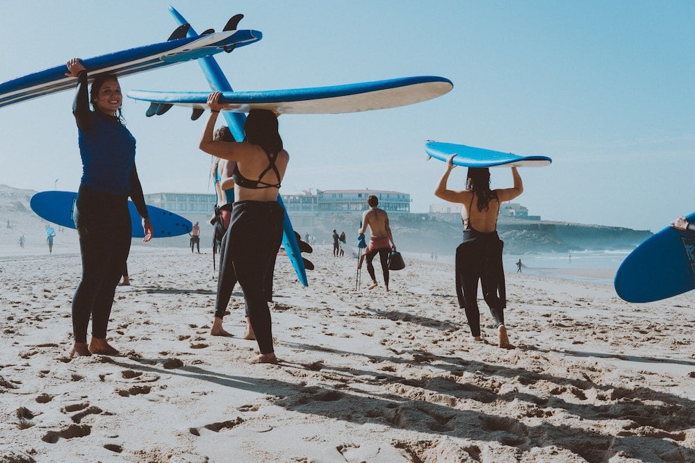 A group of surfers on the beach with sponge boards