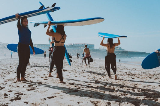 A group of surfers on the beach with sponge boards