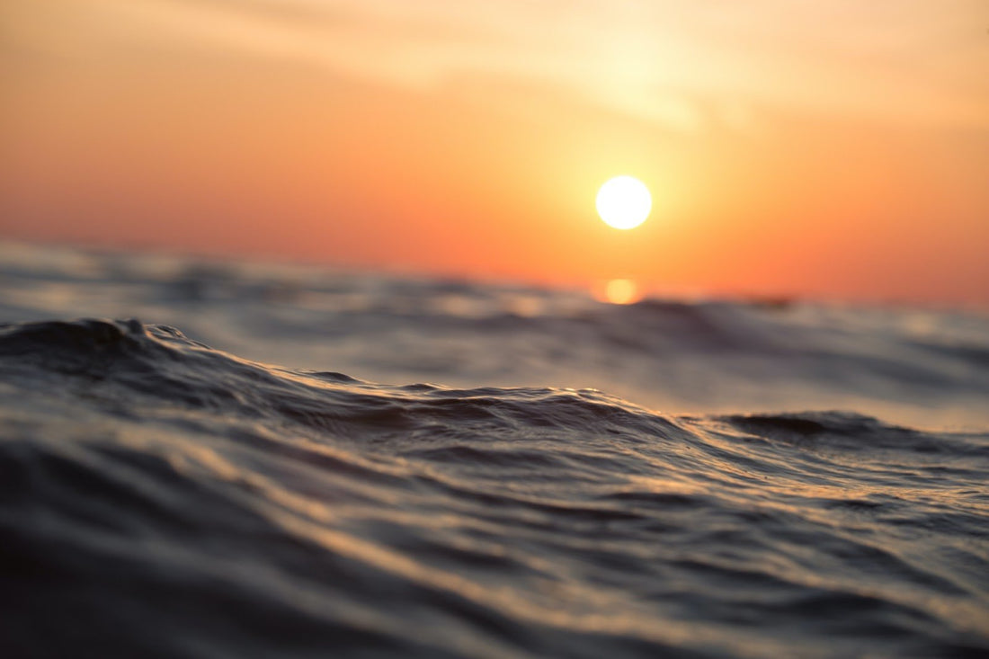 Waves in the ocean with the sun in the distance