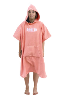 A child model wearing a coral pink hooded changing robe with the text 'SORTED' on the front.