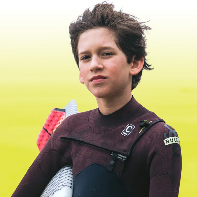 Boy wearing a wetsuit with a c-skins logo against a yellow background